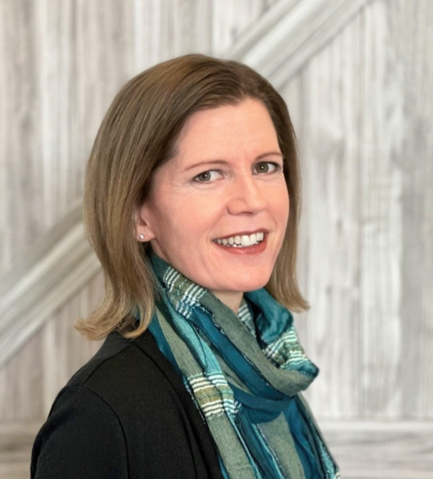Allison Hay, a smiling white woman with brown eyes and light brown hair, wearing a green scarf and dark sweater.